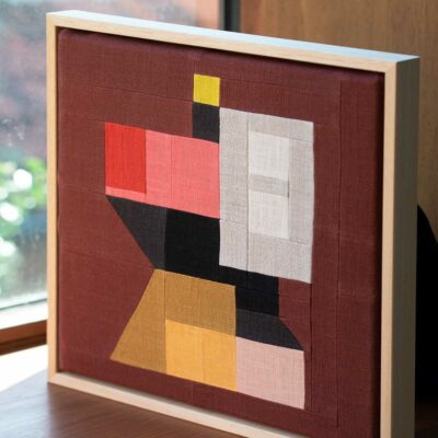 patchwork en lin représentant une architecture et encadré dans une caisse américaine